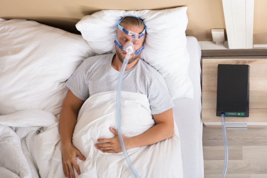 Mann mit CPAP Maske in Bett